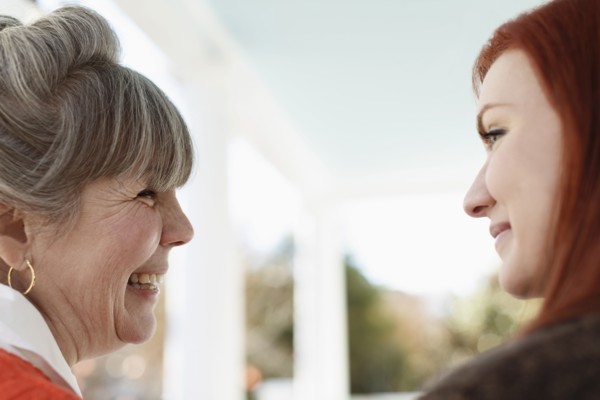 Close up of senior woman and adult daughter laughing on porch