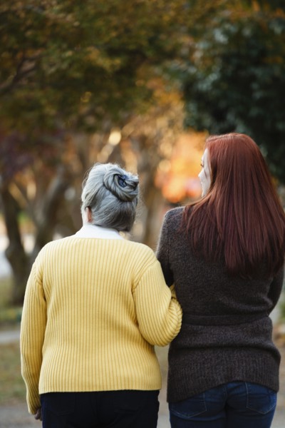 Rear view of senior woman and adult daughter strolling in autumn park