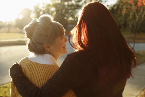 Rear view of senior woman and adult daughter strolling in park