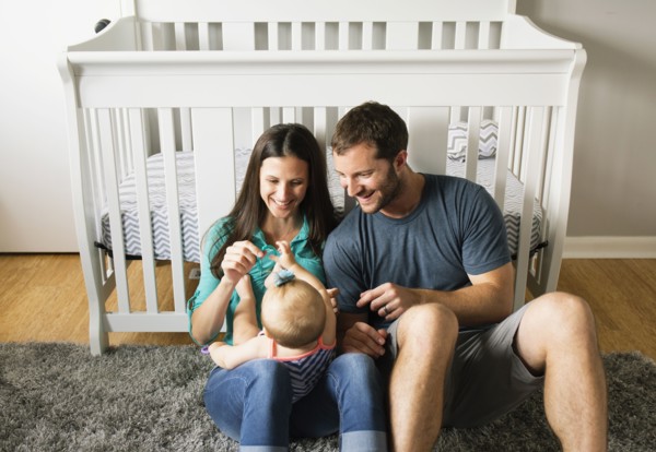 Mid adult couple playing with baby daughters fingers on lap