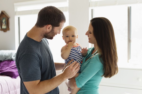 Portrait of mid adult couple with baby daughter in bedroom