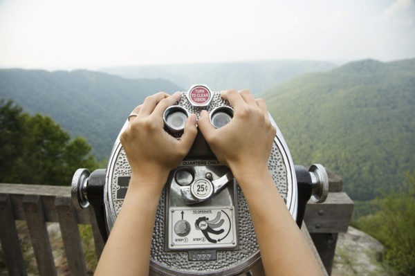 Mid adult woman holding coin operated binoculars