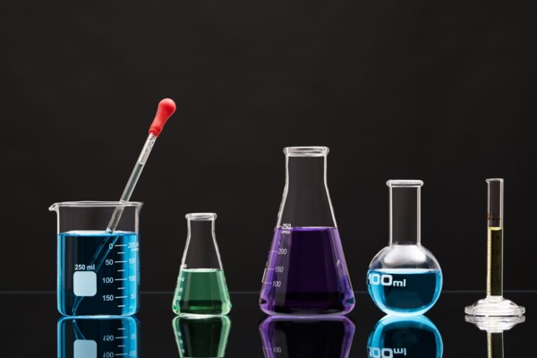 Laboratory glassware with liquids against black background