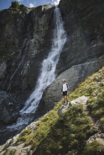 Man standing near Sofiyskiye Vodopady waterfall in Caucasus Mountains