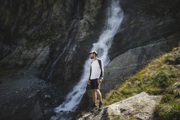 Man standing near Sofiyskiye Vodopady waterfall in Caucasus Mountains