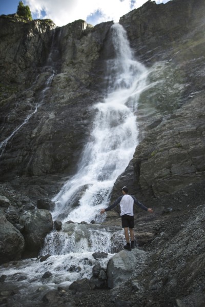 Man standing near Sofiyskiye Vodopady waterfall in Caucasus Mountains
