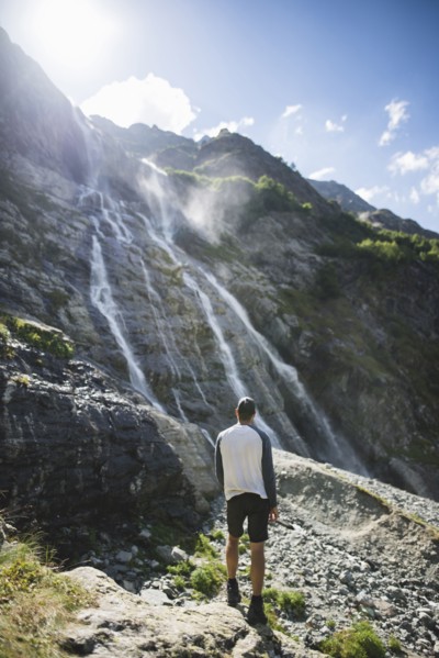 Man standing near Sofiyskiye Vodopady waterfall in Caucasus Mountains