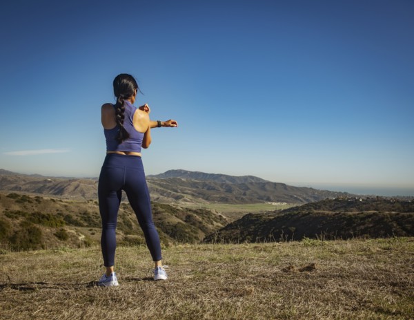 Rear view of woman stretching in landscape