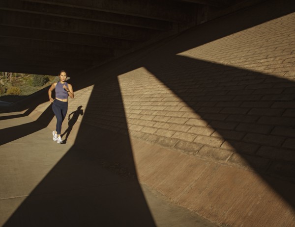 Woman jogging near brick wall in sunlight