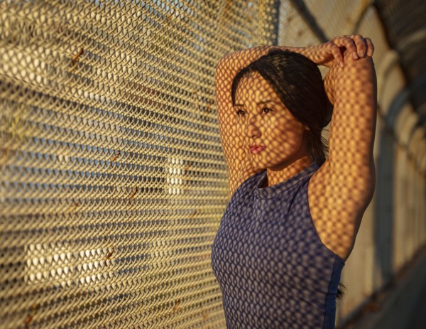 Athlete woman stretching at fence