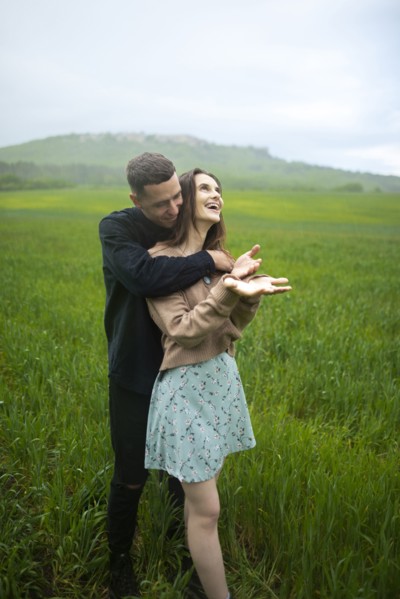 Young couple embracing in wheat field in rain