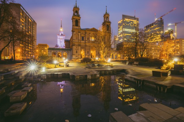 Poland, Masovia, Warsaw, Church and illuminated city skyscrapers reflecting in pond at night