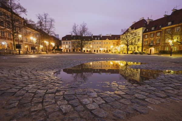 Poland, Masovia, Warsaw, Illuminated town square reflecting in puddle at night