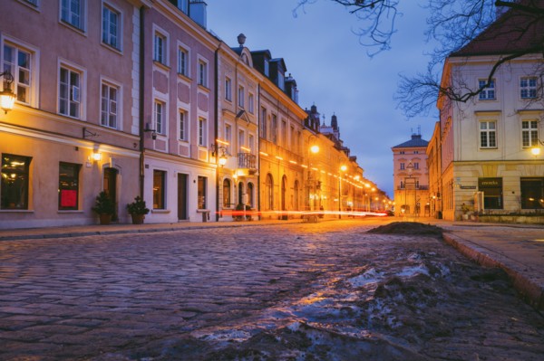 Poland, Masovia, Warsaw, Townhouses along cobblestone street in old town at night