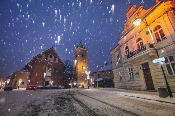 Poland, Subcarpathia, Rzeszow, Illuminated street with church in winter snowfall at night