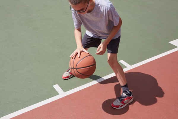 Boy dribbling basketball in park