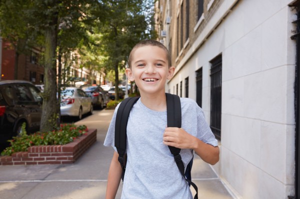 Portrait of smiling Boy wearing backpack in city