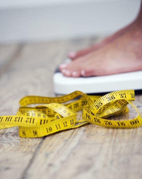 Tape measure next to woman standing on scale