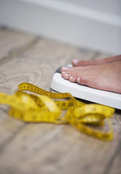 Tape measure next to woman standing on scale