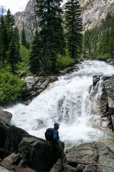 Man hiking by mountain waterfall
