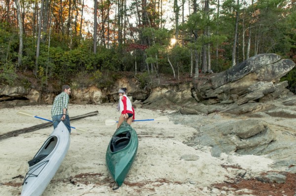 Couple pulling kayaks on rocks