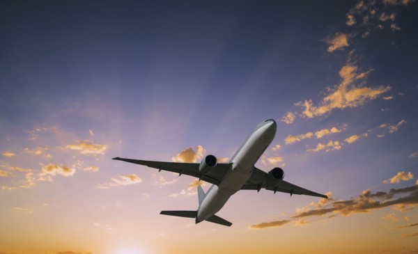 Airplane flying in dramatic sunset sky