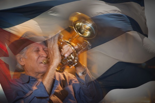 Double exposure of Hispanic musician playing trumpet in front of Cuban flag
