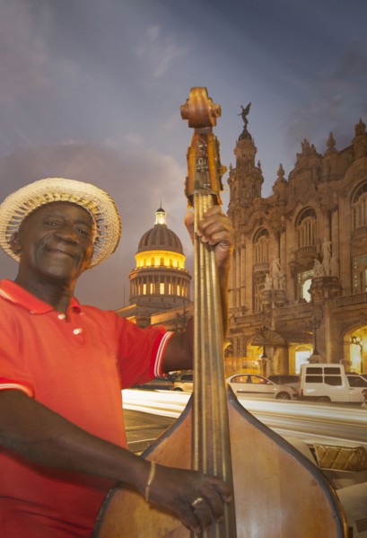 Hispanic musician playing upright bass in city