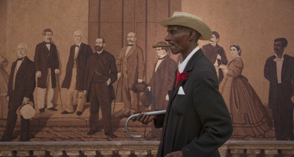 Hispanic man walking past mural