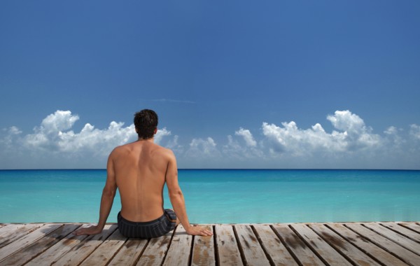 Caucasian man sitting on wooden dock at ocean