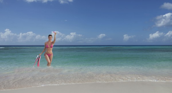 Caucasian woman wading on beach with flippers and snorkel