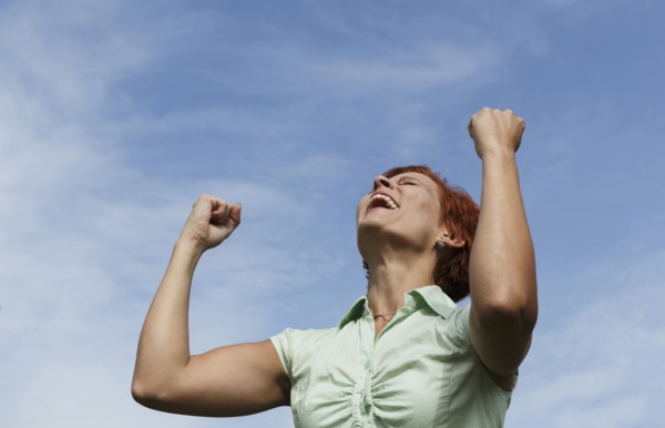 Caucasian woman cheering under blue sky