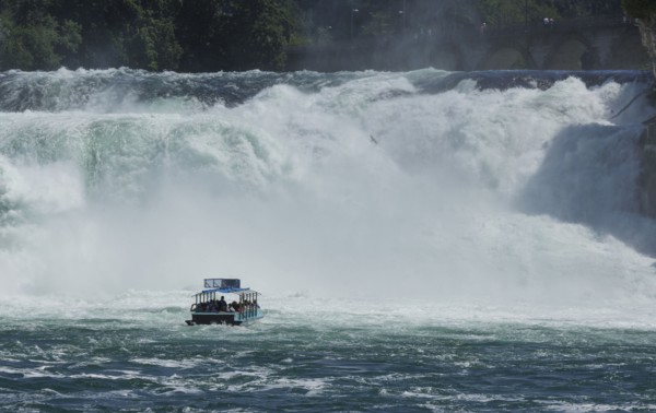 Boat floating near dramatic waterfall
