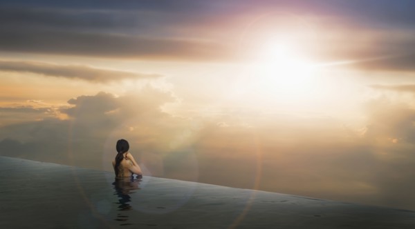 Chinese woman in infinity pool admiring sunset