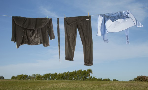 Wet business suit hanging on clothesline in field