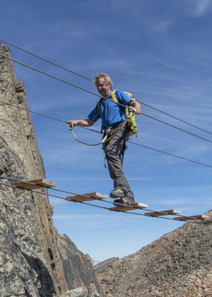 Caucasian man crossing rope bridge on mountain