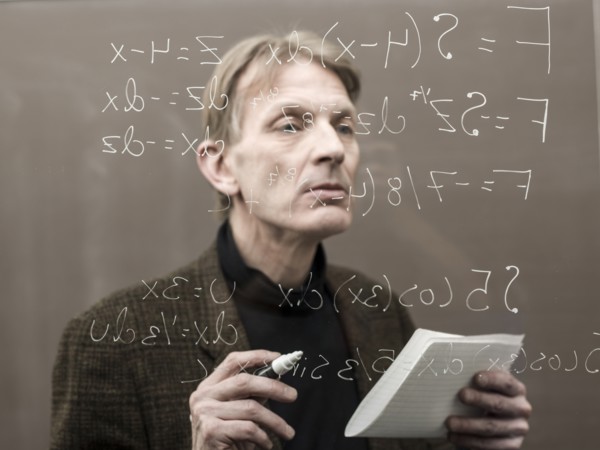 Caucasian teacher looking at formula on glass wall