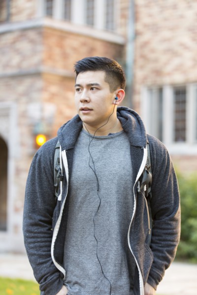 Mixed race college student listening to music on headphones