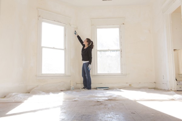 Mixed race woman painting walls of new home