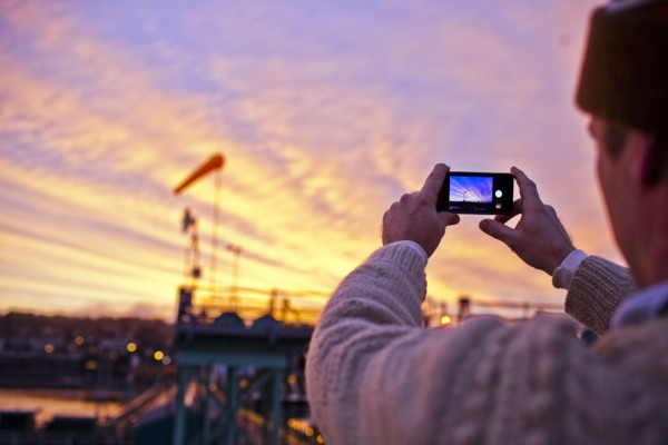Man taking picture of sunset over bridge