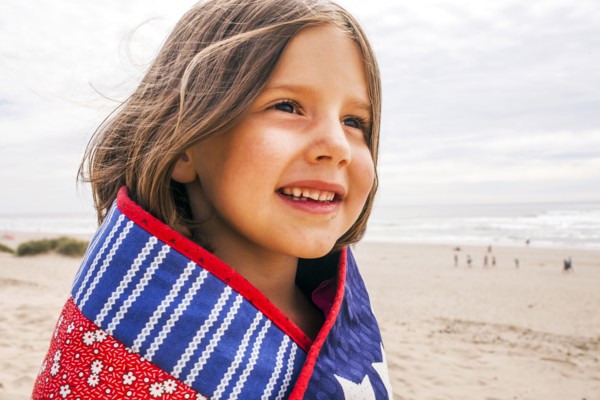 Caucasian girl wrapped in blanket on beach