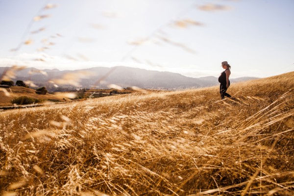 Pregnant Caucasian woman walking in rural meadow