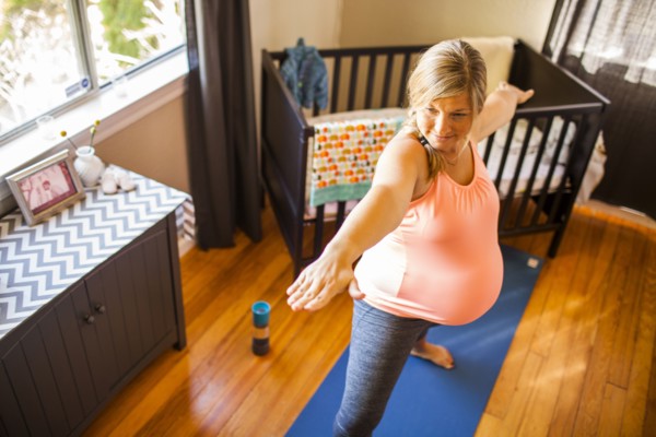 Pregnant Caucasian woman practicing yoga in nursery