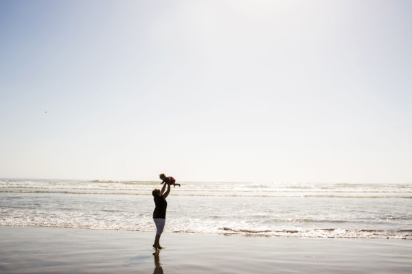 Caucasian mother lifting baby daughter on beach