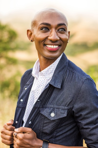 Smiling gay Black man holding denim jacket