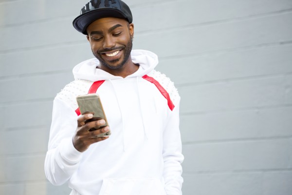 Smiling Black man texting on cell phone