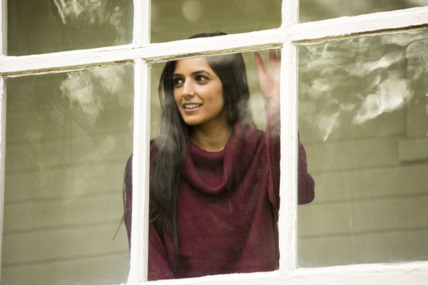 Smiling Indian woman leaning on window