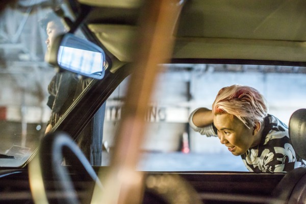 Androgynous Asian woman checking hair in side-view mirror
