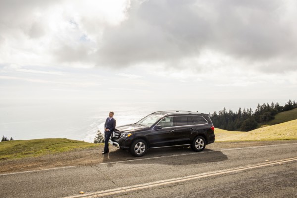 Distant Caucasian businessman leaning on car