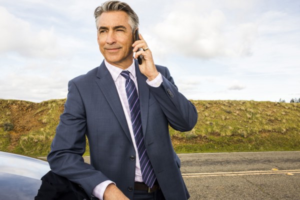 Caucasian businessman leaning on car talking on cell phone